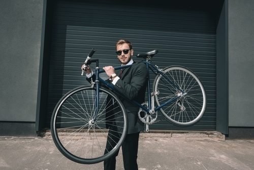 businessman holding his hybrid bike over his shoulder