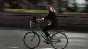 woman riding a green step-through bicycle