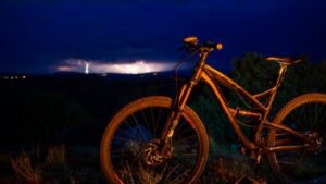 a mountain bike standing while a lightning storm is seen in the background