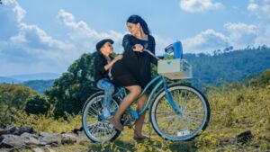 a pregnant woman riding a bicycle with her son