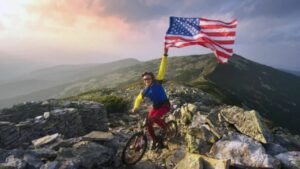 man on a maountain bike holding a usa flag