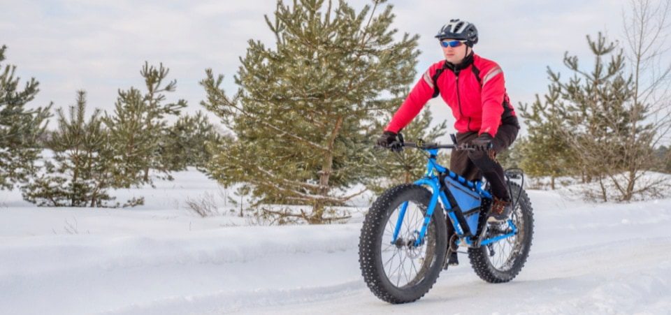 a cyclist is riding his fat tire mountain bike in winter