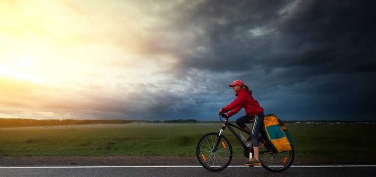 a woman riding her bicycle under a cloudy sky