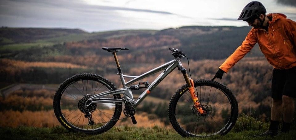 man standing touching his full suspension bike